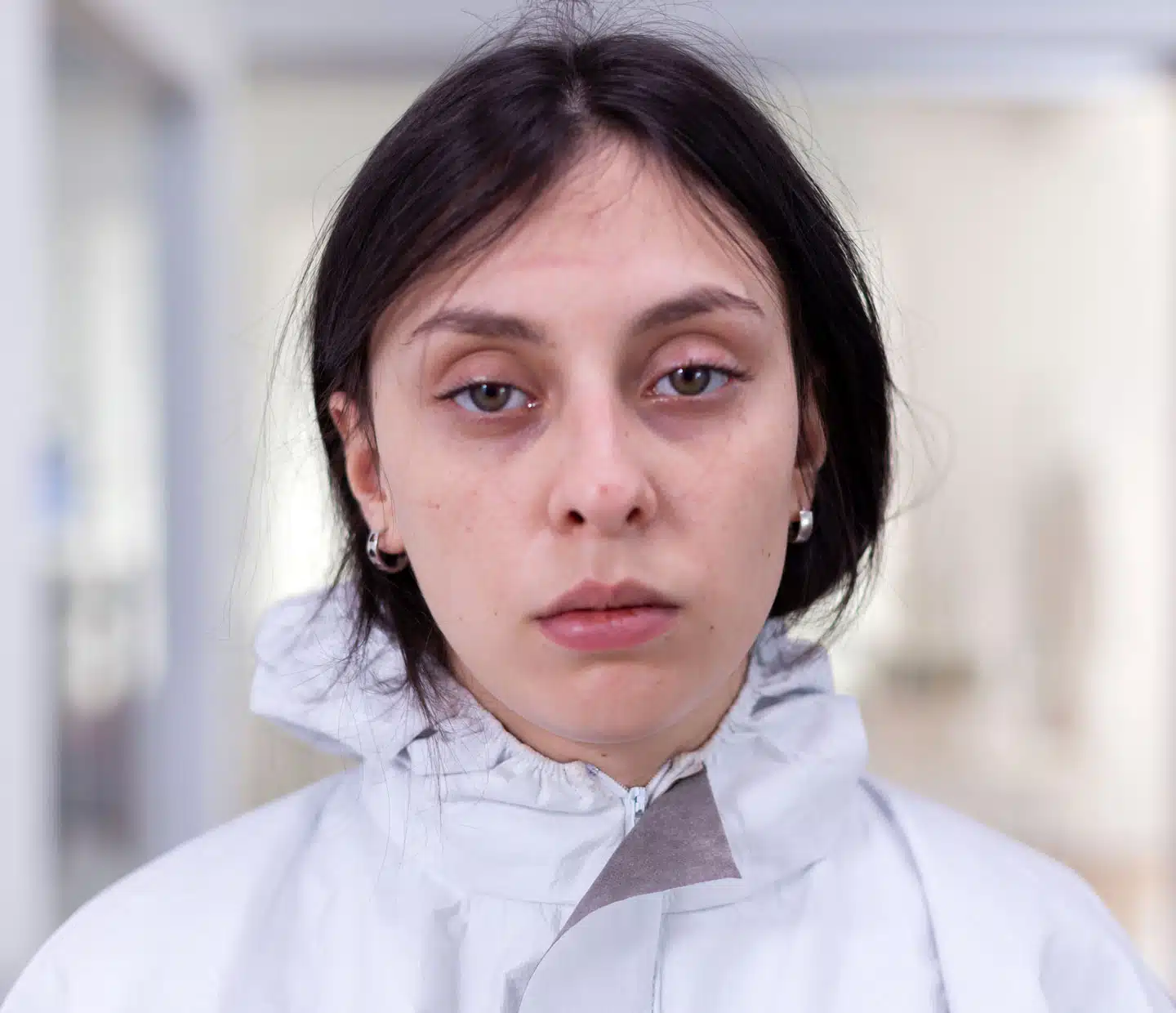 Close up of exhausted nurse in office looking on camera wearing ppe suit