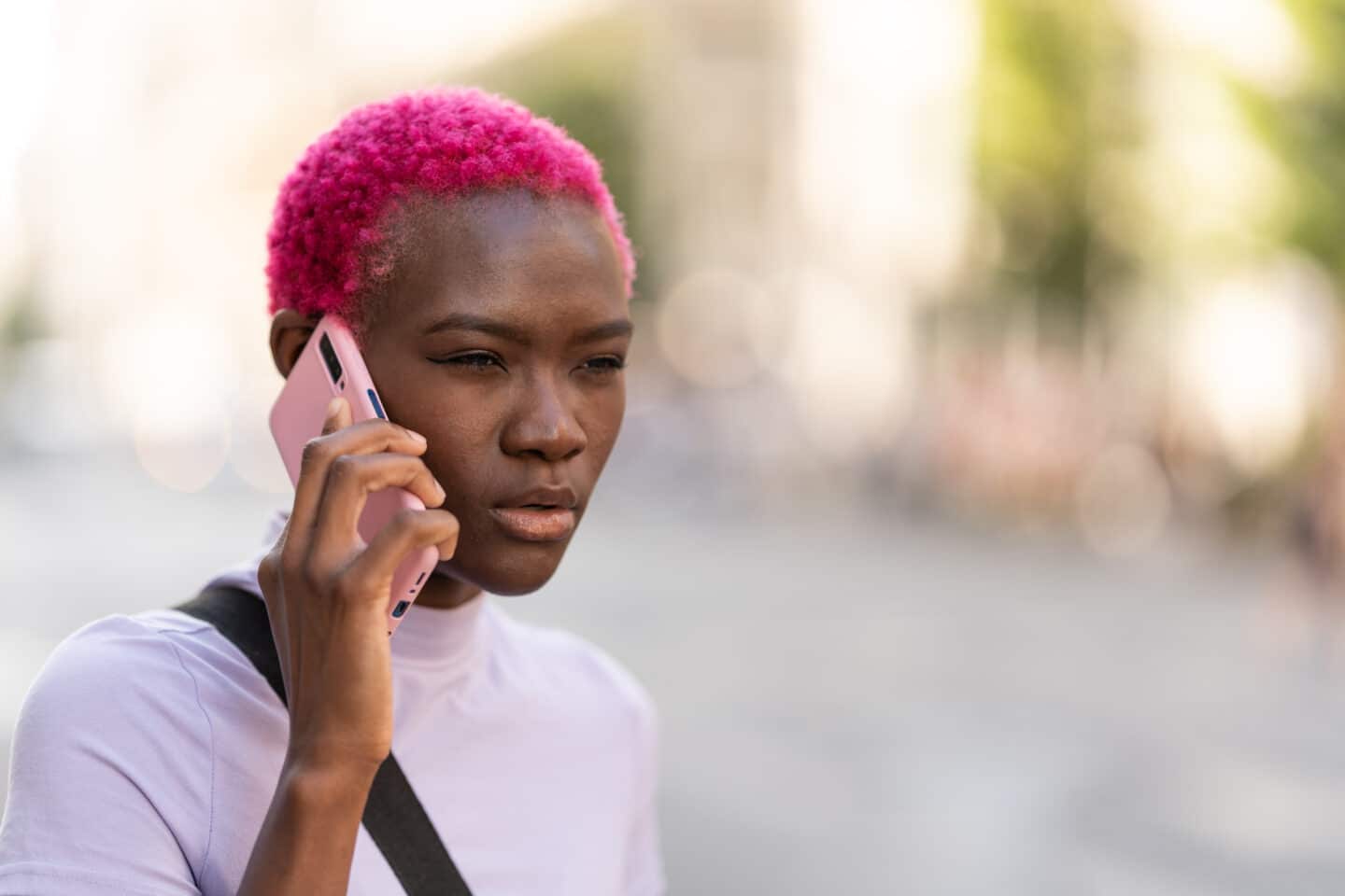 Portrait of a young african woman with a distrustful expression talking on a mobile in the street