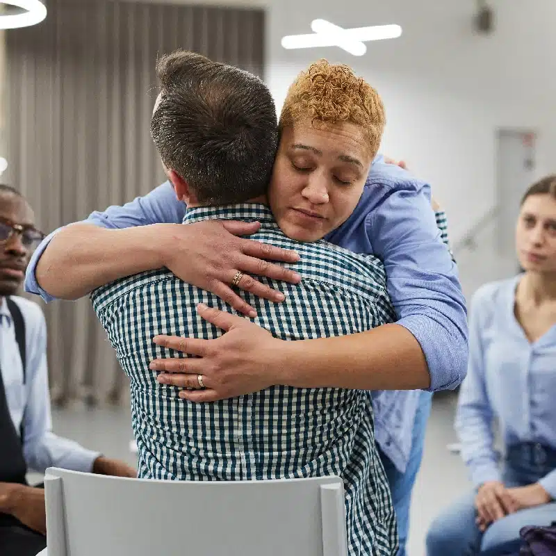 Portrait of mixed race woman hugging psychologist during therapy session in support group, copy space