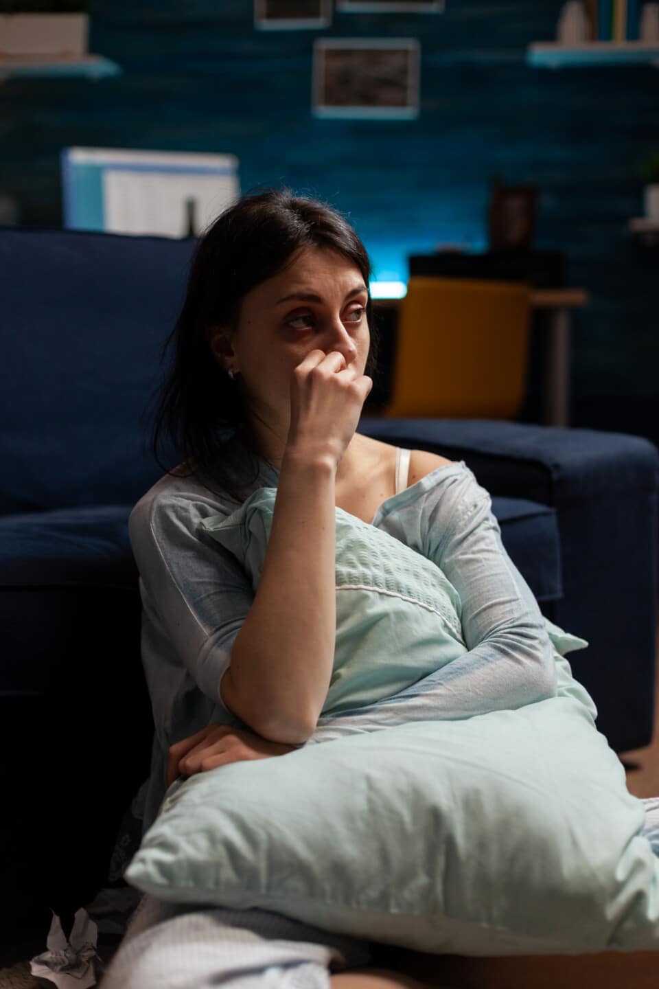 Depressed suicidal woman sitting on living room floor, feeling frustrated and having chronic mental disease difficulties. Anxious female person dealing with sadness and negativity.