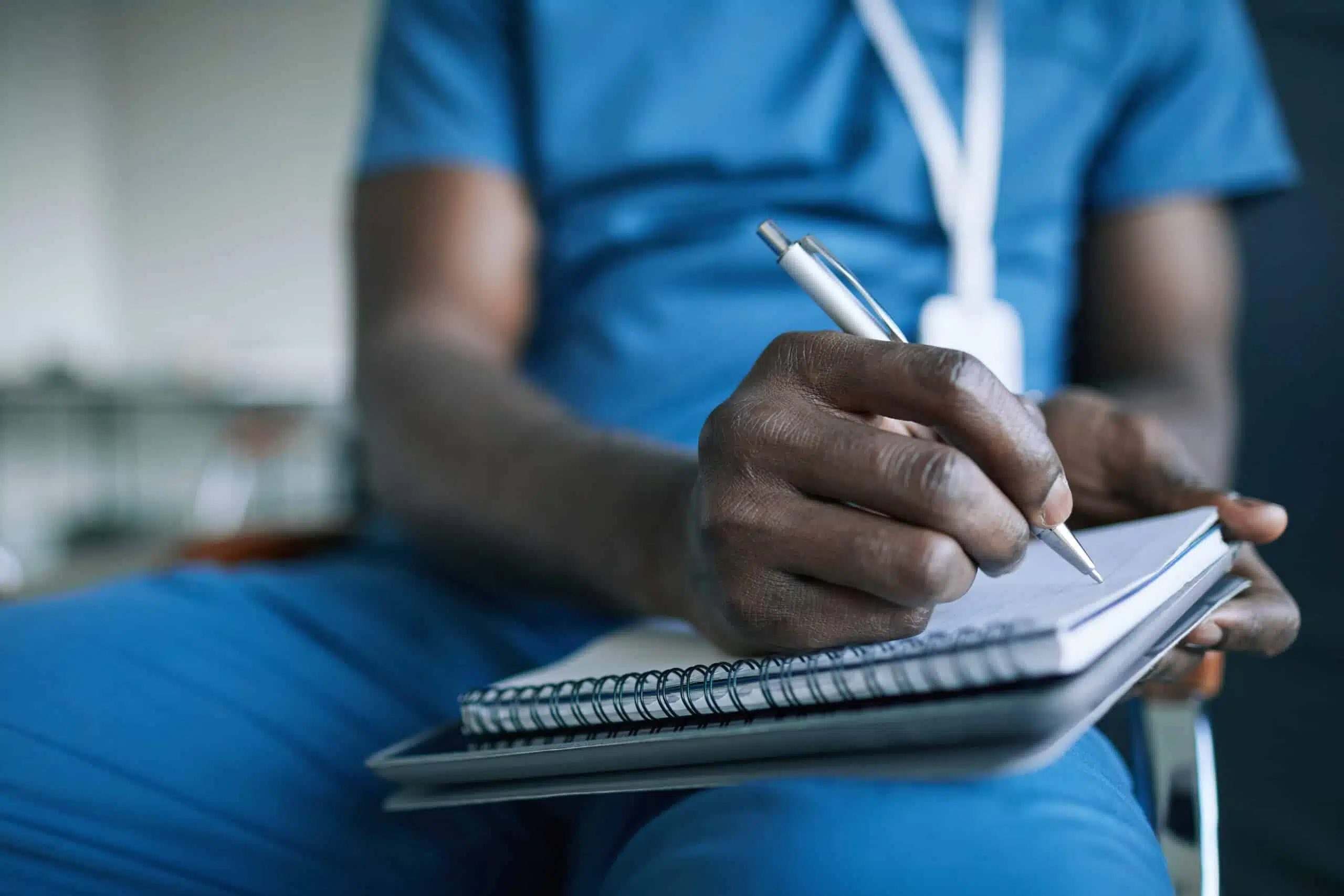 Close up of unrecognizable African-American doctor taking notes while attending medical conference or seminar, copy space