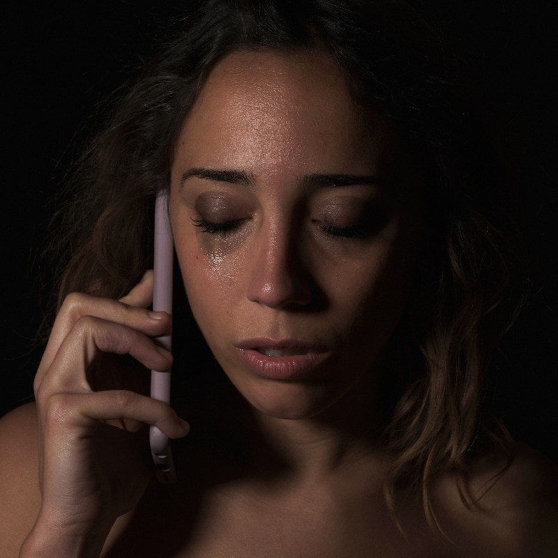 Female victim of domestic abuse phoning support group. Calling for help.