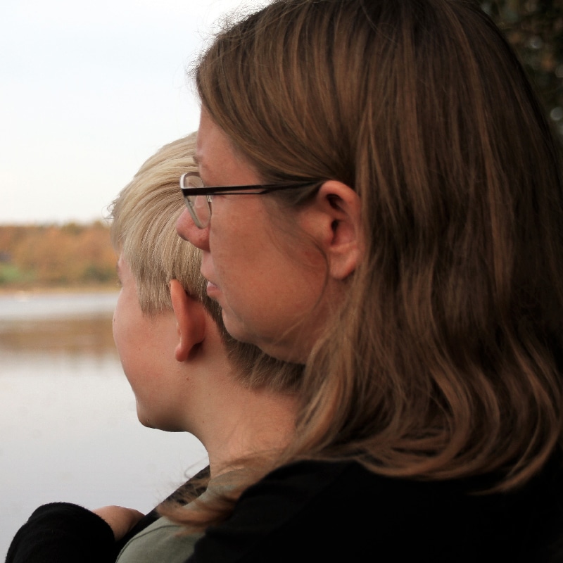 Mom and teenage son, looking out over the lake. Melancholic feeling, mental health, family, sorrow