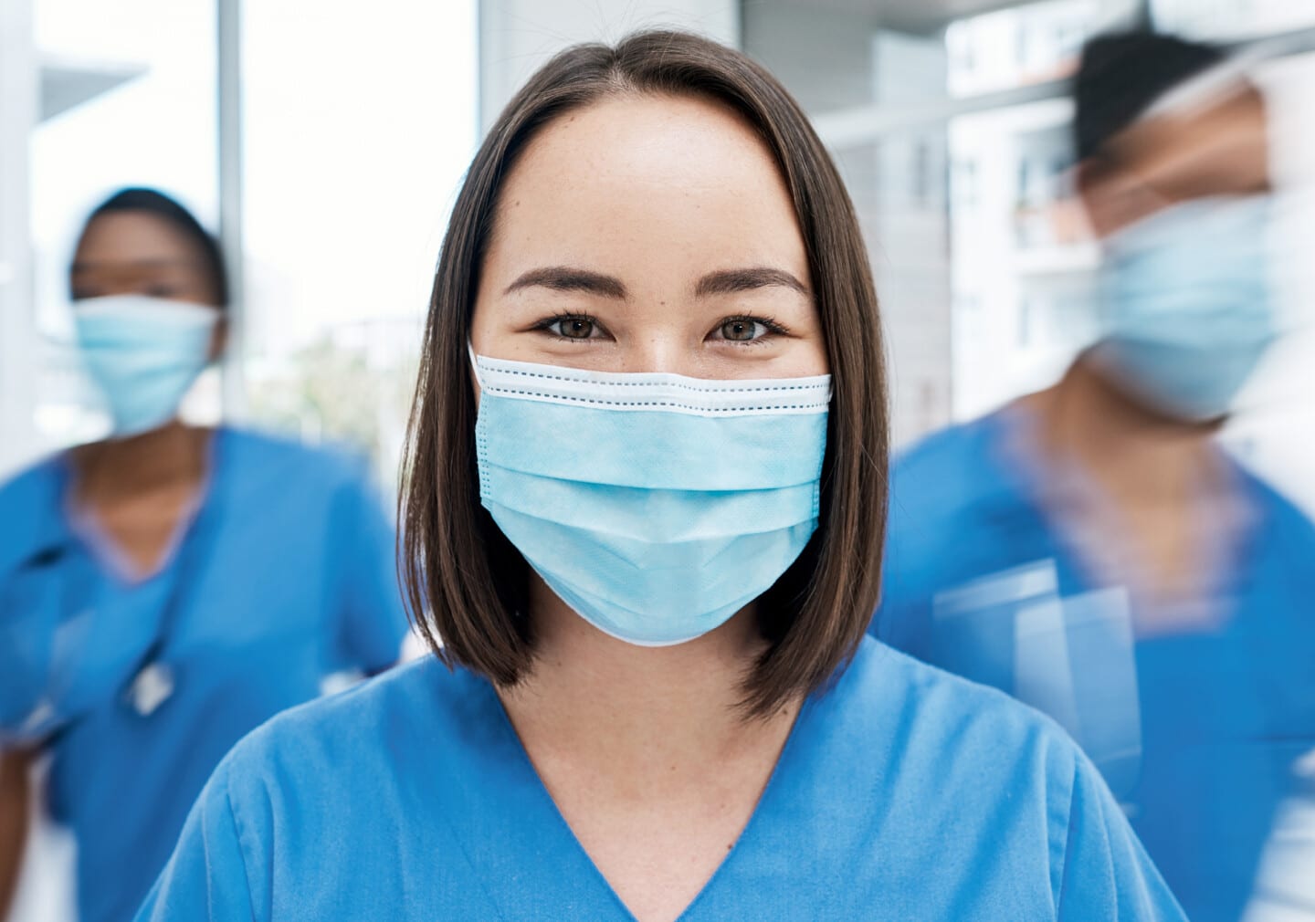 Portrait of a doctor wearing a face mask in a busy hospital.