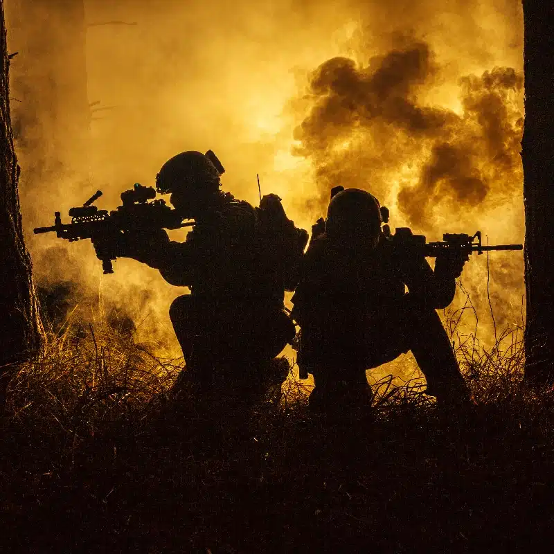 Backlit silhouette of special forces marine operators in forest on fire explosion background